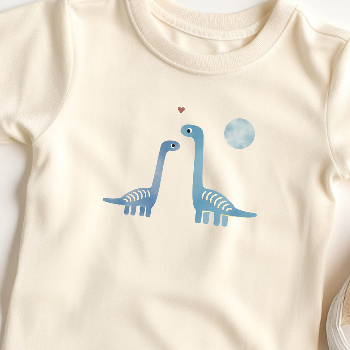 Bügelbild mit zwei Dinosauriern und Herz im liebevollen Design, ideal zum Aufbügeln auf Kinderkleidung und Accessoires.