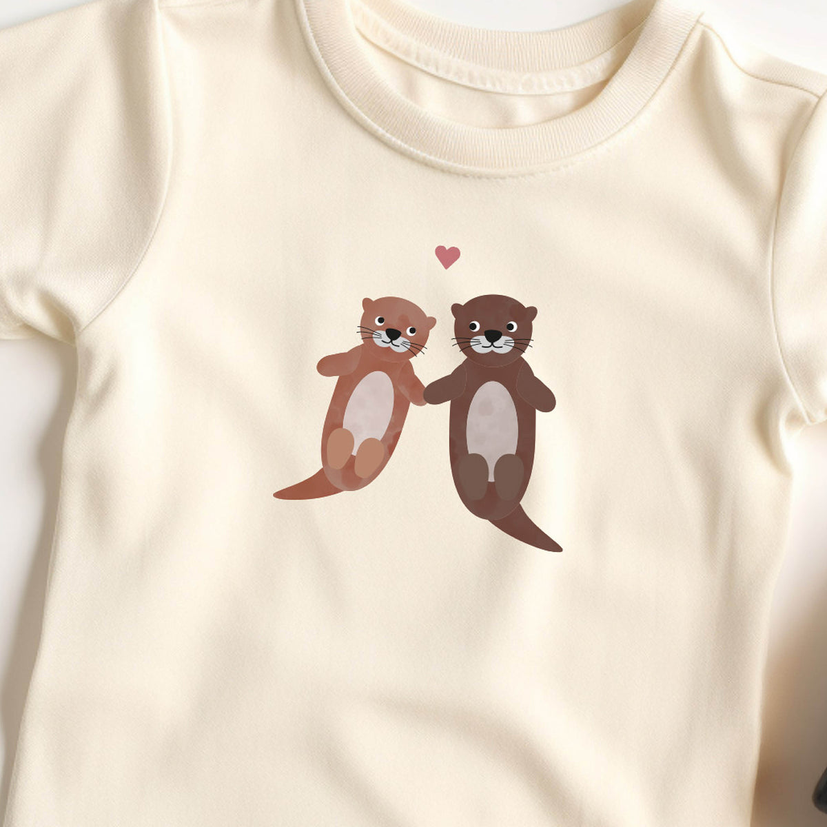 Bügelbild mit der Illustration zweier liegenden Otters auf transparentem Hintergrund