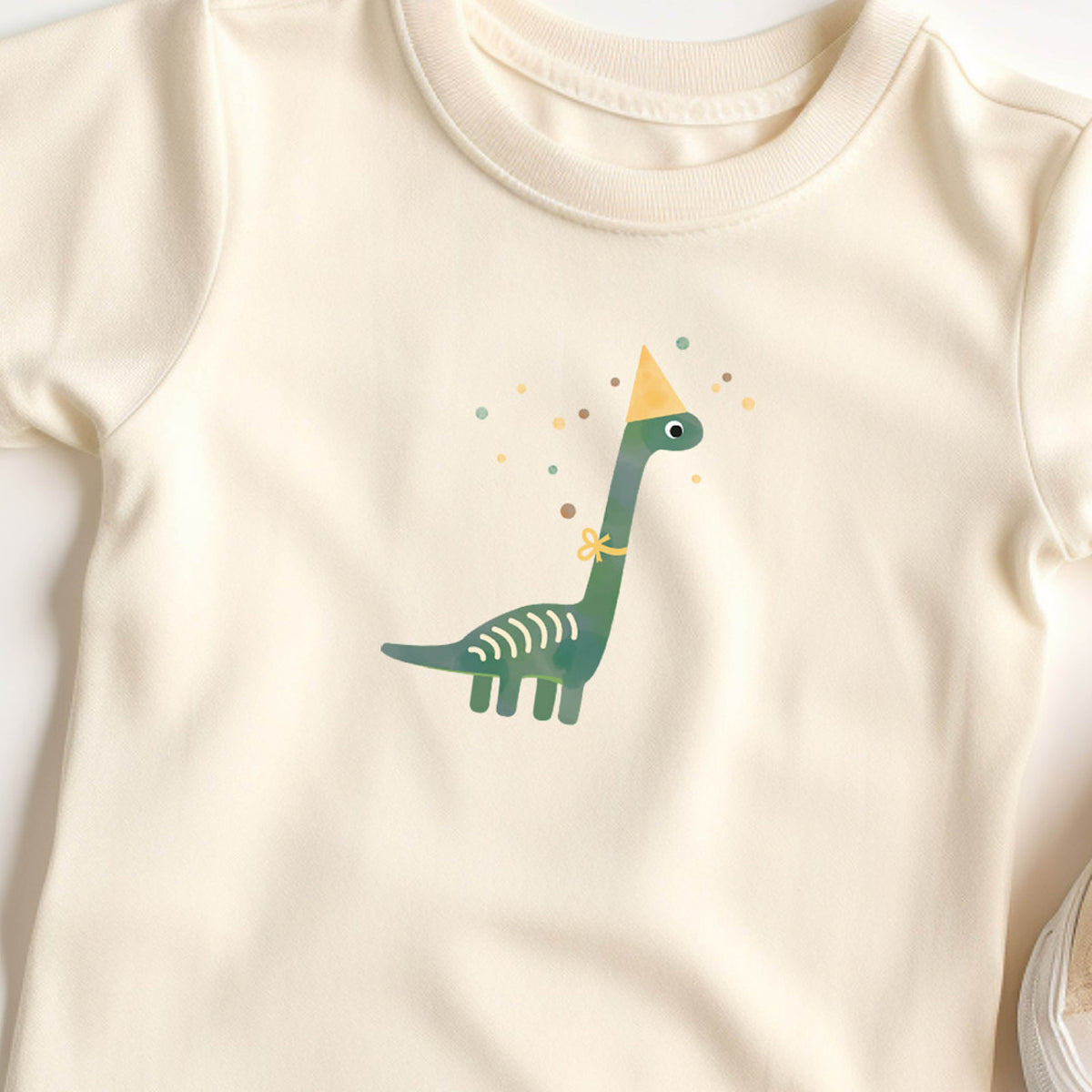 Bügelbild mit Dino und Partyhut im fröhlichen Design, perfekt zum Aufbügeln auf Kinderkleidung und Accessoires.