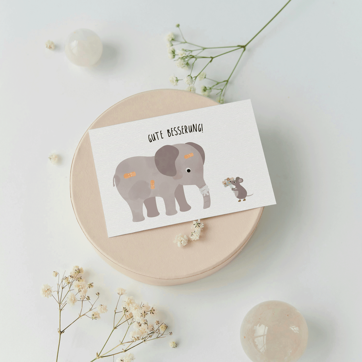 Grußkarte mit der Illustration eines Kuscheltiers im Krankenbett und dem Text „Gute Besserung“ auf hellem Hintergrund
