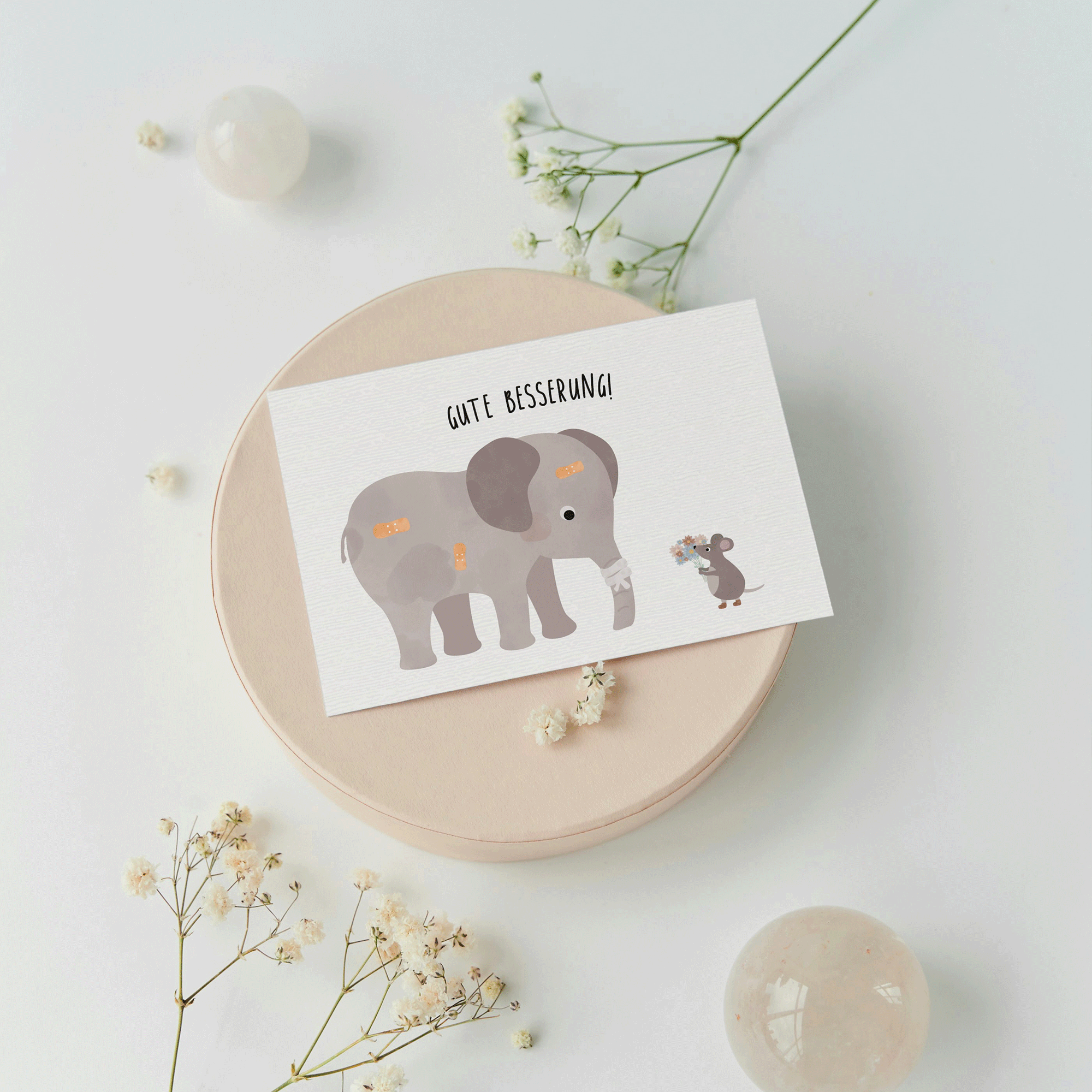 Grußkarte mit der Illustration eines Kuscheltiers im Krankenbett und dem Text „Gute Besserung“ auf hellem Hintergrund