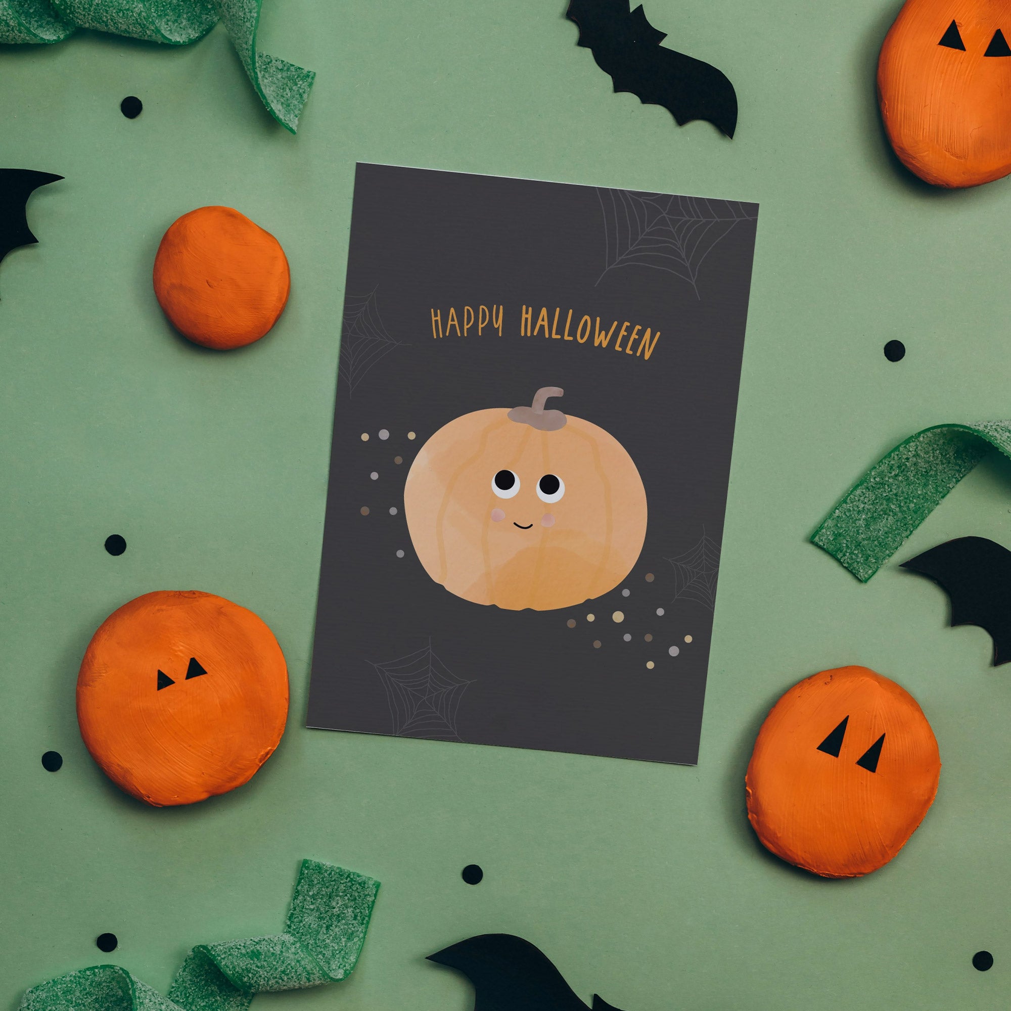 Illustration einer Halloween-Grußkarte mit einem lächelnden Kürbis und der Aufschrift „Happy Halloween“ auf orangem Hintergrund