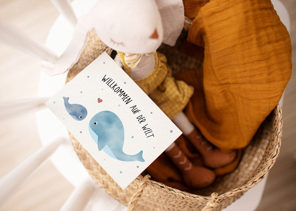 Postkarte mit Wal und dem Schriftzug „Willkommen auf der Welt“ im niedlichen Design, ideal als Geburtskarte oder Willkommensgruß für Babys.