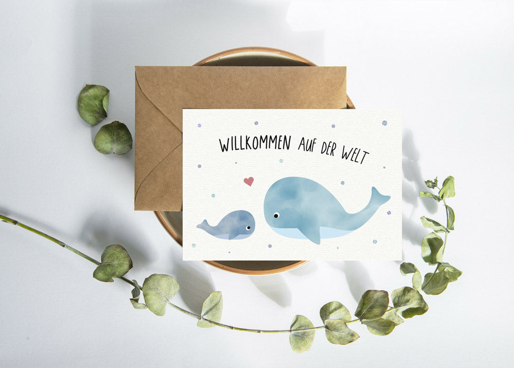 Postkarte mit Wal und dem Schriftzug „Willkommen auf der Welt“ im niedlichen Design, ideal als Geburtskarte oder Willkommensgruß für Babys.