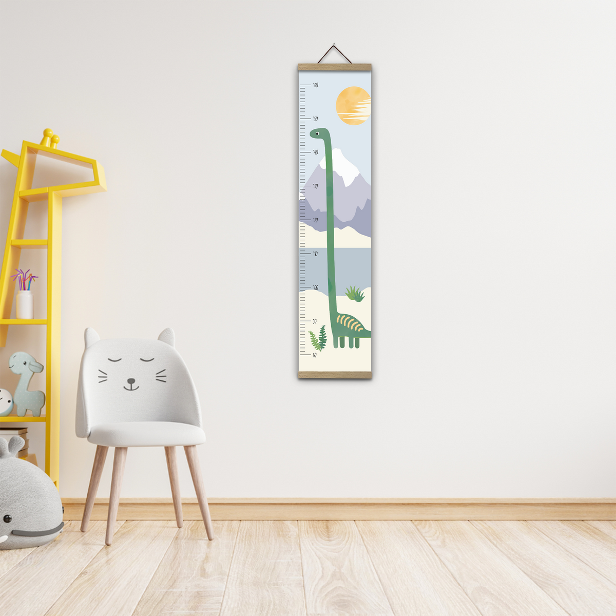 Kinderzimmer mit einem weißen Stuhl, der wie ein Katzengesicht gestaltet ist, neben einem gelben Regal. An der Wand hängt ein Kindermaßband mit einem Dinosauriermotiv und einer Berg- und Sonnenszene.