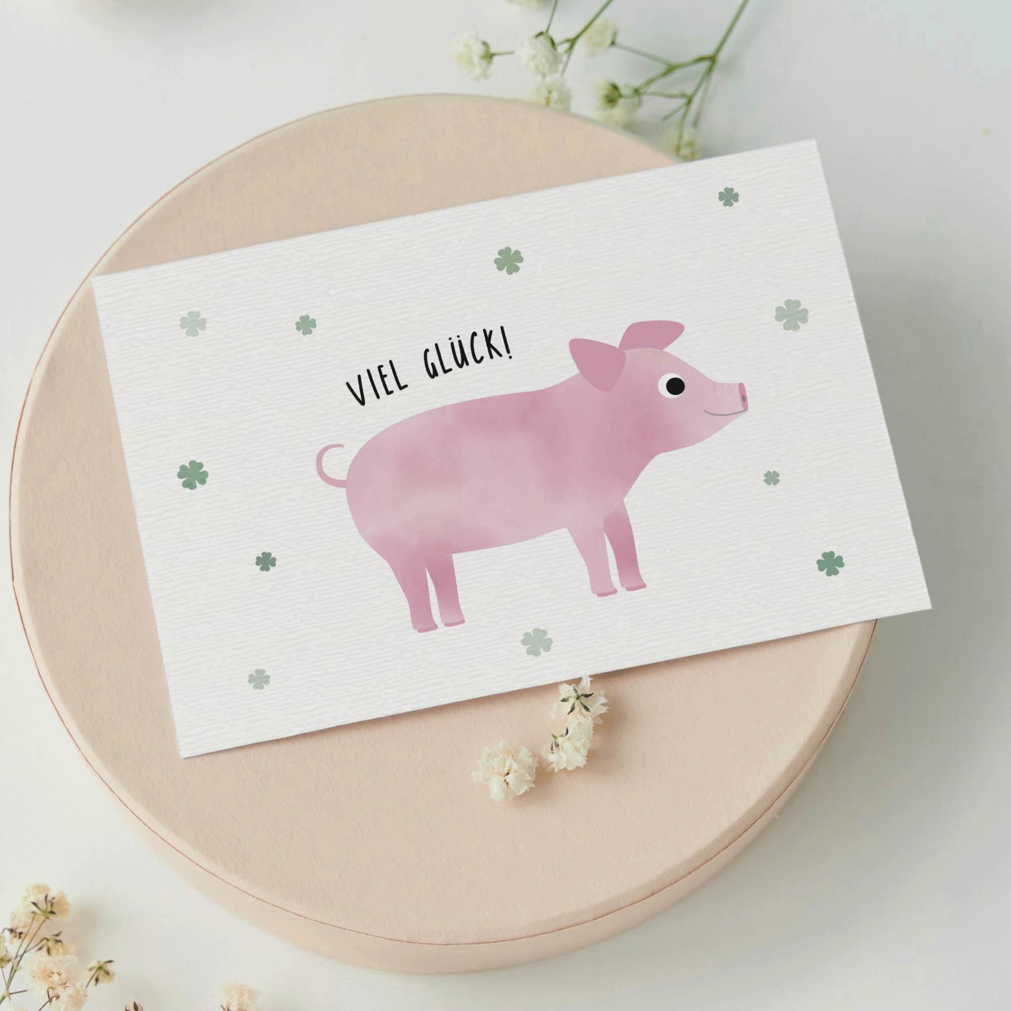 Grußkarte mit der Illustration eines rosa Glücksschweins und dem Text „Viel Glück“ auf hellem Hintergrund