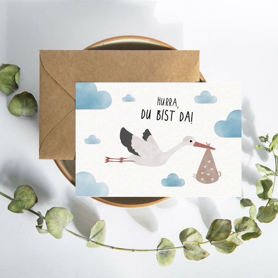 Postkarte mit Storch und dem Schriftzug „Hurra du bist da“ im niedlichen Design, ideal als Geburtskarte oder Willkommensgruß für Babys.
