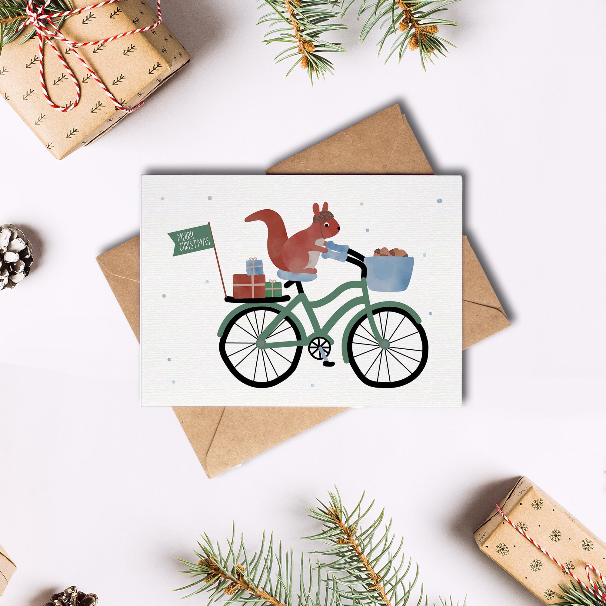 Postkarte mit Eichhörnchen auf einem Fahrrad mit Geschenken und dem Schriftzug „Merry Christmas“ im niedlichen Design, ideal als Weihnachtskarte oder kleiner Gruß.