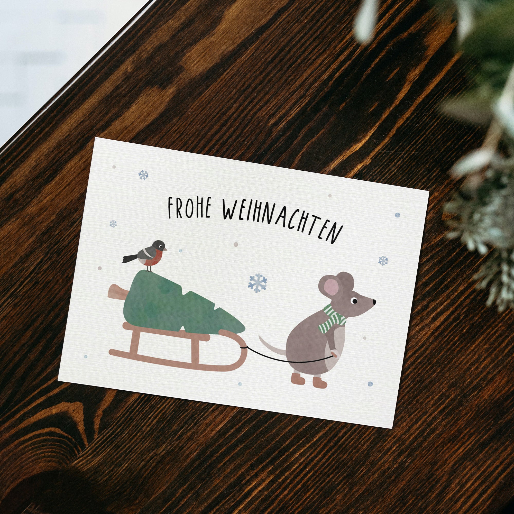 Postkarte mit Maus, die einen Schlitten zieht, und dem Schriftzug „Frohe Weihnachten“ im niedlichen Winterdesign, ideal als Weihnachtskarte oder kleiner Gruß.