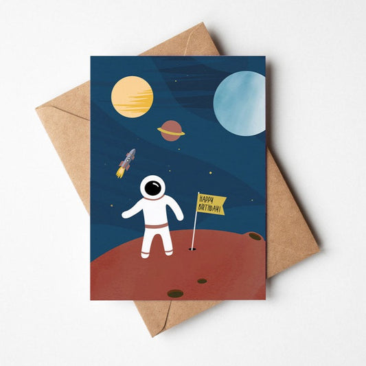 Postkarte mit Astronaut der auf einem roten Planeten steht. Im Hintergrund sieht man Planeten und eine Rakete