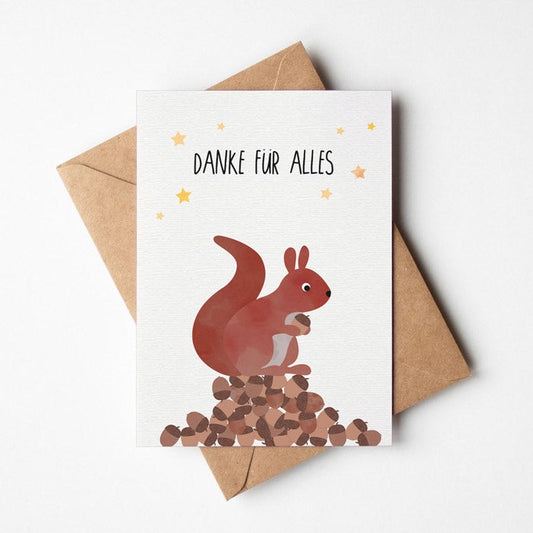 Postkarte mit Eichhörnchen welches auf einem Berg Nüsse sitzt