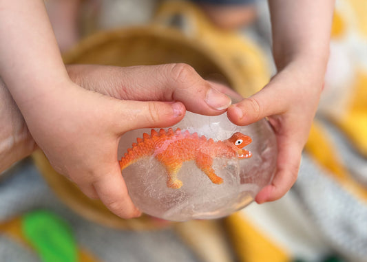 Ein Kind hält ein Dino Ei aus Eis in den Händen