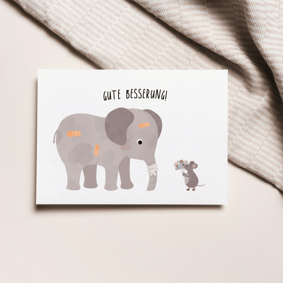 Grußkarte mit der Illustration eines Kuscheltiers im Krankenbett und dem Text „Gute Besserung“ auf hellem Hintergrund