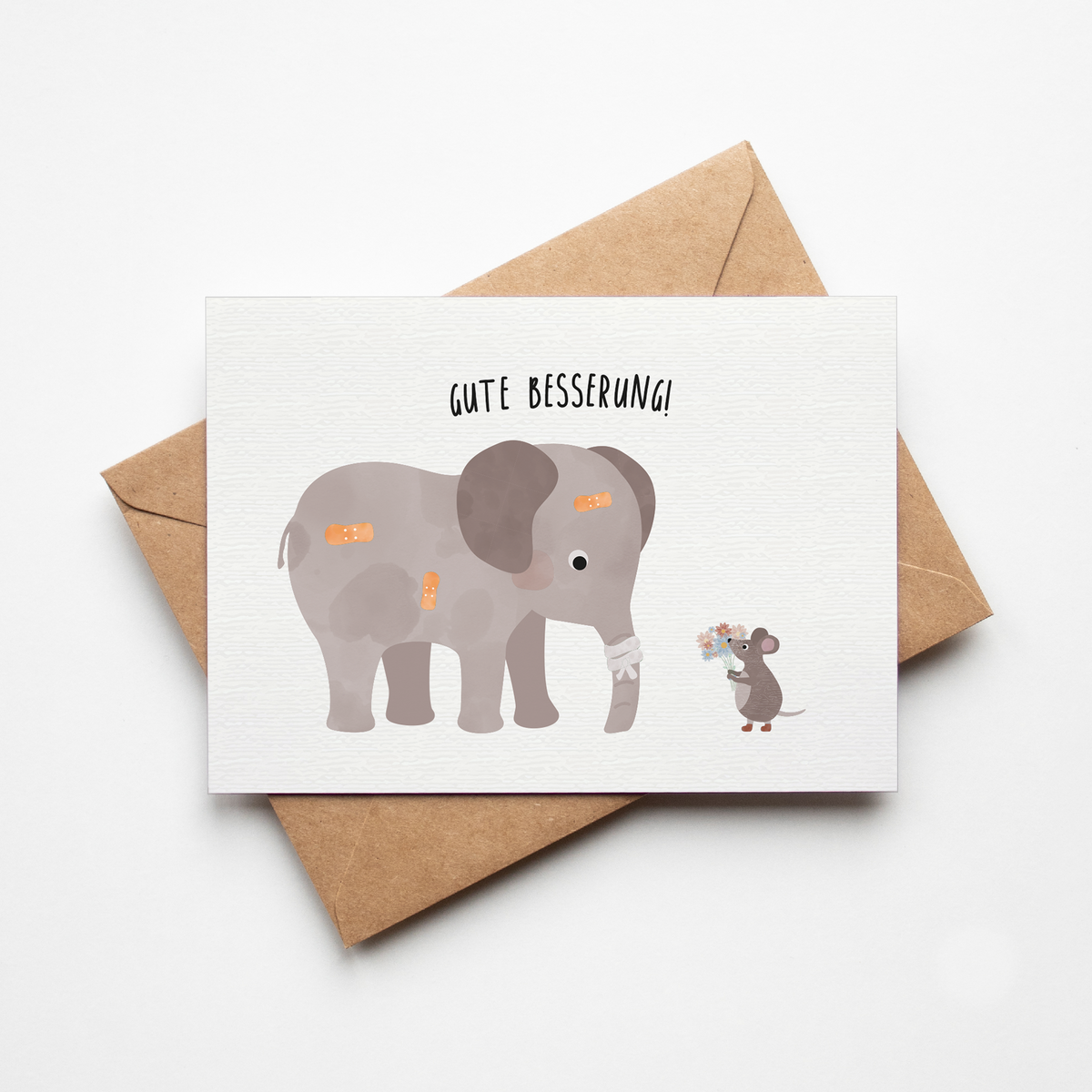 Grußkarte mit der Illustration eines Kuscheltiers im Krankenbett und dem Text „Gute Besserung“ auf hellem Hintergrund