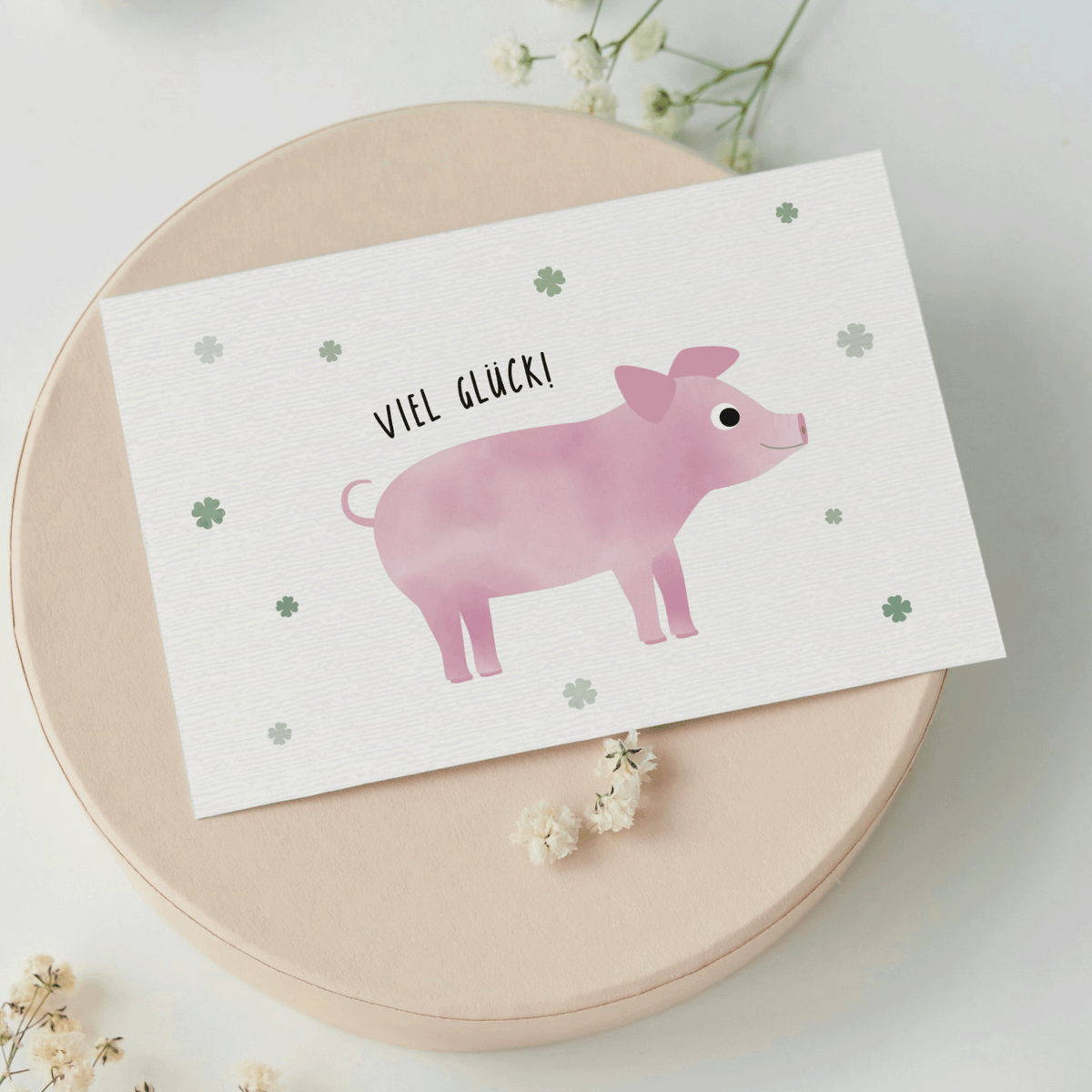 Grußkarte mit der Illustration eines rosa Glücksschweins und dem Text „Viel Glück“ auf hellem Hintergrund