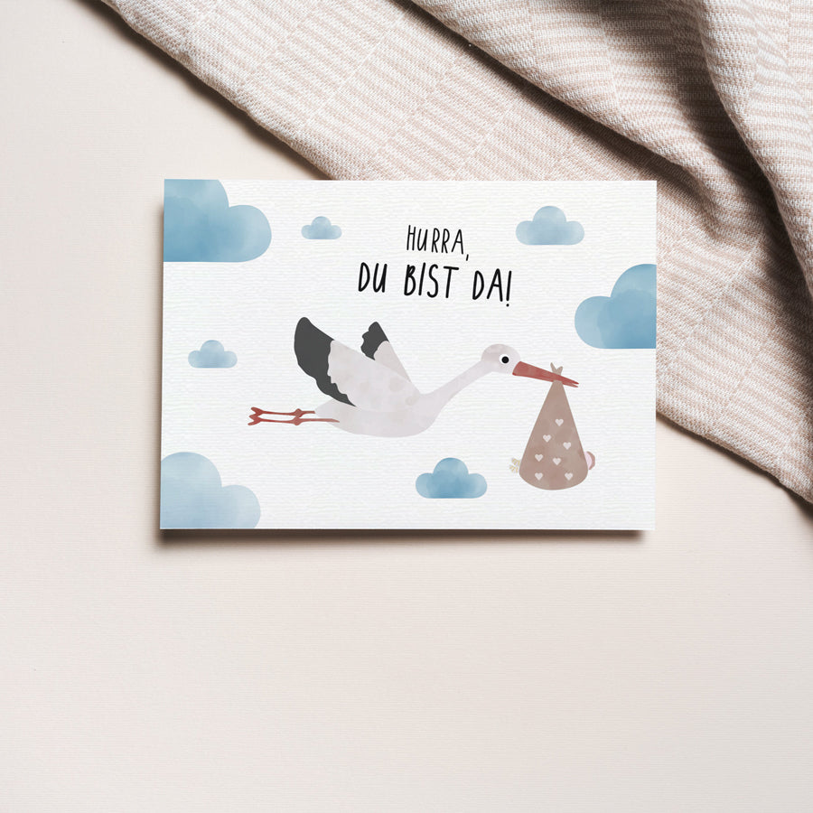 Postkarte mit Storch und dem Schriftzug „Hurra du bist da“ im niedlichen Design, ideal als Geburtskarte oder Willkommensgruß für Babys.