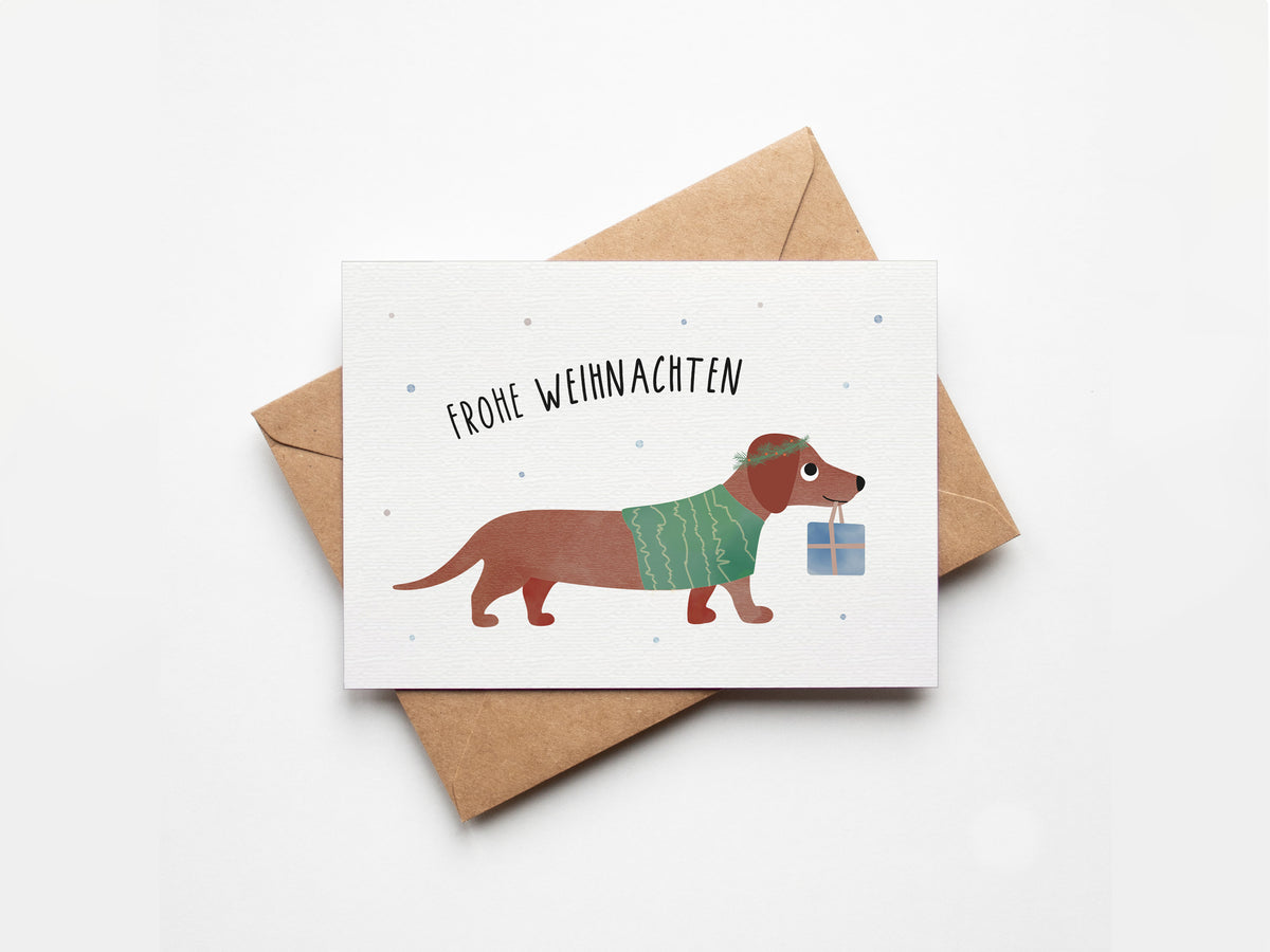 Postkarte mit Dackel im Auto und einem Tannenbaum auf dem Dach sowie dem Schriftzug „Frohe Weihnachten“ im niedlichen Design, ideal als Weihnachtskarte oder kleiner Gruß.